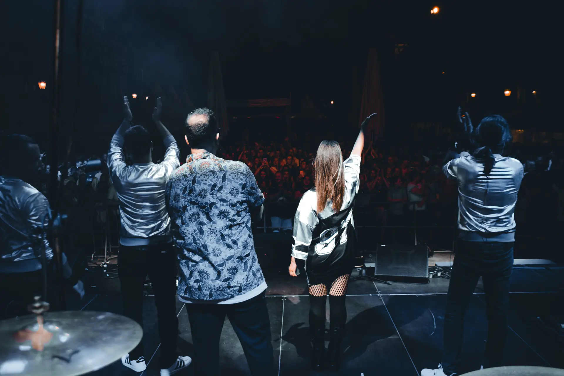 Die Band von hinten auf der Bühne, vor ihnen das feiernde Publikum – JENNY AND THE GANG